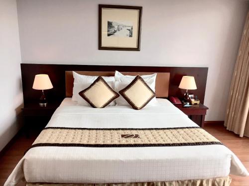 a bedroom with a large bed with two lamps at Mondial Hotel Hue in Hue