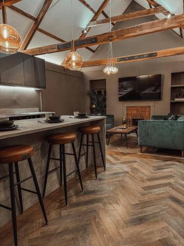 a kitchen with a bar with stools and a couch at Magistrates Penthouse Suite - Town Centre Apartments with Spa in Morpeth