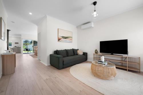 a living room with a couch and a flat screen tv at YARLU by Silver Sands in Aldinga Beach