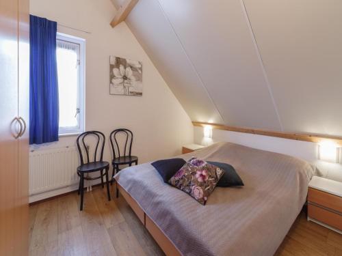 a bedroom with a bed and two chairs in it at Holiday Home in Peaceful Dutch Park with Terrace in Wemeldinge