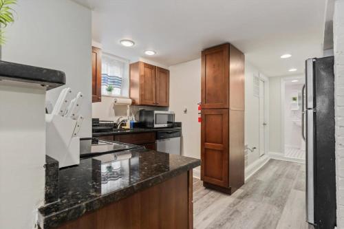 a kitchen with wooden cabinets and a black counter top at Garden-Level 2-BR Apt in Historic Petworth Home in Washington, D.C.