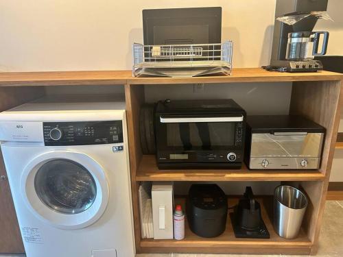 a shelf with a microwave and a washing machine at 真鶴町ペットと泊まれてBBQも可能な広々ワンフロア貸切apartment Hotel途乃中RC1 in Manazuru