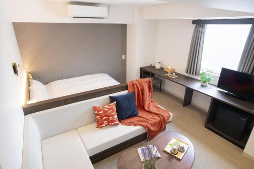 a small room with a bed and a couch at WAYFARER Matsu in Osaka