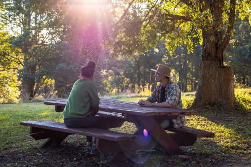 two people sitting at a picnic table in a park at Krishna Farm Retreat in Coolabine