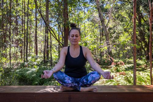 a woman sitting in a yoga pose in the woods at Krishna Farm Retreat in Coolabine