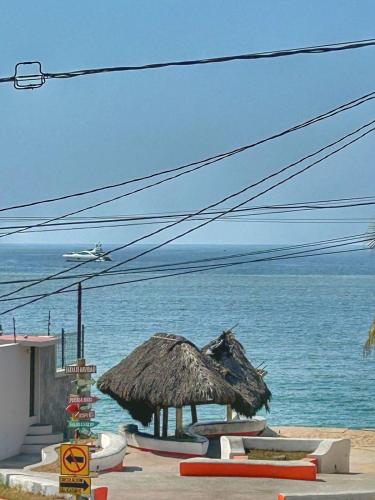a beach with a straw umbrella and the ocean at Apartment 4 Maleconcito del Sol Barra de Navidad in Barra de Navidad