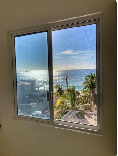 a room with a window with a view of the ocean at Apartment 4 Maleconcito del Sol Barra de Navidad in Barra de Navidad