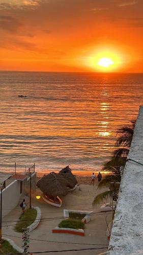 a sunset on a beach with the sun setting over the ocean at Apartment 4 Maleconcito del Sol Barra de Navidad in Barra de Navidad