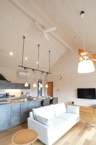 a living room with a white couch and a kitchen at パインズコテージ八ヶ岳 トゥースラ in Hokuto