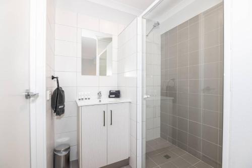 a white bathroom with a shower and a sink at Jurien Bay Motel Apartments in Jurien Bay