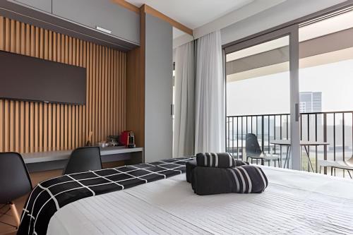 a bedroom with a large bed with a flat screen tv at Nik Perdizes in Sao Paulo