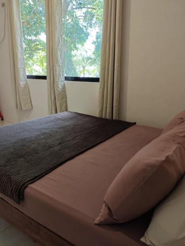 a bed in a bedroom with two windows at Buhay Probinsya - Bubolongan in El Nido