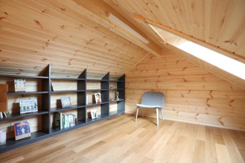 an attic room with a chair and bookshelves at パインズコテージ八ヶ岳 トゥースラ in Hokuto