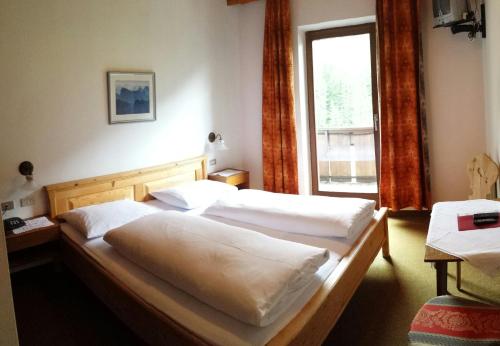 two beds in a room with a window at Berghotel Kason in Predoi