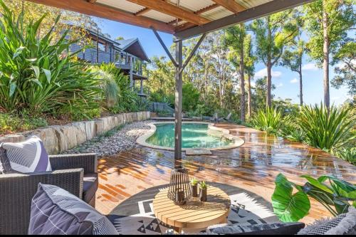 an outdoor patio with a pool and a table at Gold Coast Mountain Retreat in Mount Tamborine