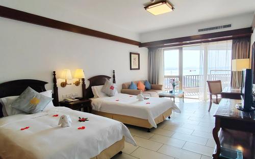a hotel room with two beds and a living room at Timton Fuhe Hotel in Sanya