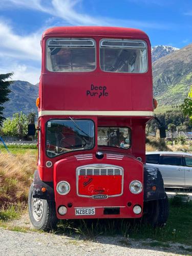a red double decker bus parked in the grass at Decker Daze Queenstown in Queenstown