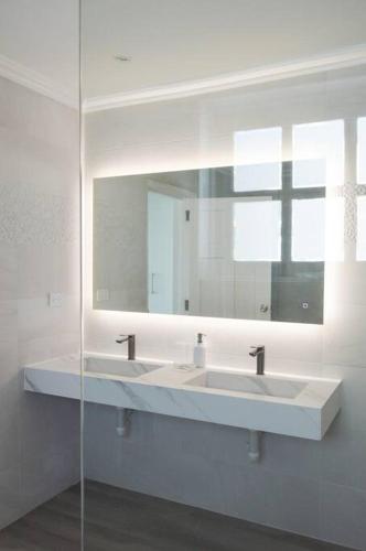 a white bathroom with two sinks and a mirror at Rose Villa Tobago in Auchenskeoch