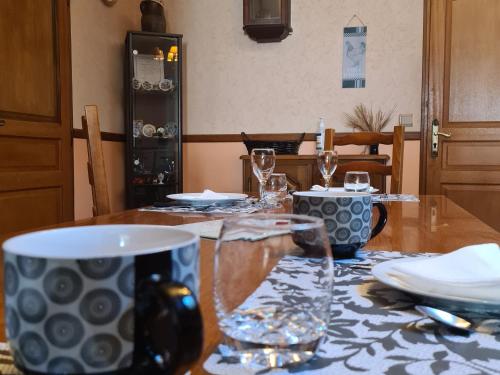 - une table en bois avec des verres et des assiettes dans l'établissement Gîte et camping à la ferme avec espace détente - Profitez de la campagne du Berry - FR-1-591-558, à La Berthenoux