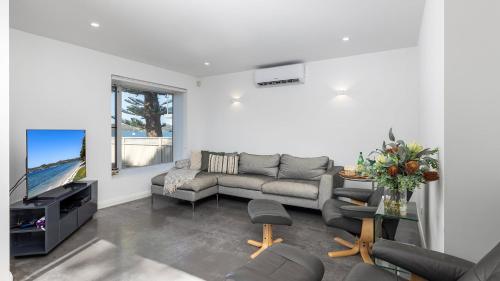 a living room with a couch and a tv at Foreshore Bliss in Salamander Bay