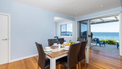 a dining room with a table and chairs and the ocean at Foreshore Bliss in Salamander Bay
