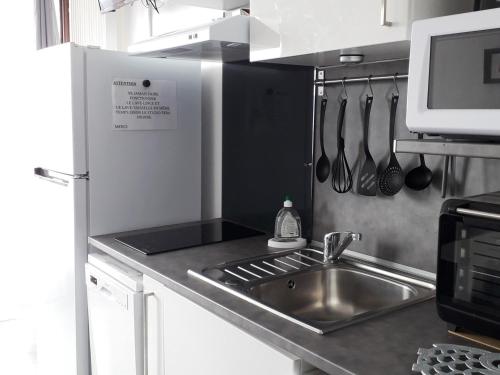 une cuisine avec un évier et un comptoir avec des ustensiles dans l'établissement Studio cabine 4 pers, station Côte 2000, tout équipé - FR-1-689-138, à Villard-de-Lans