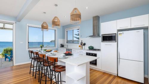 a kitchen with a table with chairs and a white refrigerator at Foreshore Bliss in Salamander Bay