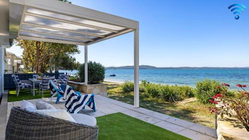 a patio with chairs and a view of the water at Foreshore Bliss in Salamander Bay