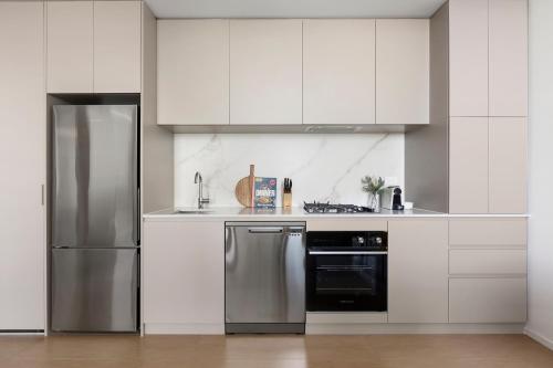 a kitchen with white cabinets and a stainless steel refrigerator at Caulfield Apartments by Urban Rest in Melbourne