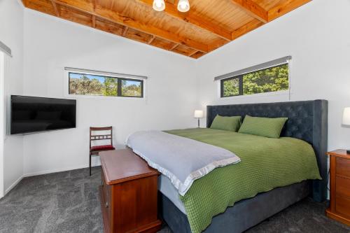 a bedroom with a bed and a flat screen tv at Waitorupai Retreat 2 - Sandy Bay Holiday Home in Whangarei