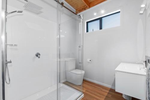 a bathroom with a glass shower and a toilet at Waitorupai Retreat 2 - Sandy Bay Holiday Home in Whangarei