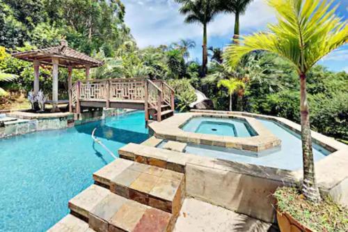 a pool with a bridge and a palm tree at Hawaiian Dream Temple in Kaupakulua