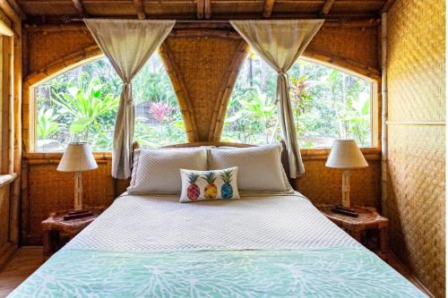 a bedroom with a bed with two lamps and a window at Hawaiian Dream Temple in Kaupakulua