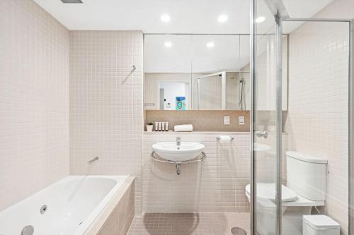un bagno con vasca, lavandino e WC di Belle Escapes - Beachside Apartment in Glenelg a Glenelg