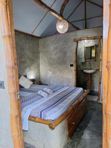 a bedroom with a bed with a wooden frame and a sink at Yucca Bungalow in El Nido