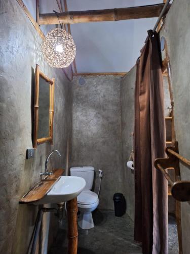 a bathroom with a sink and a toilet and a chandelier at Yucca Bungalow in El Nido