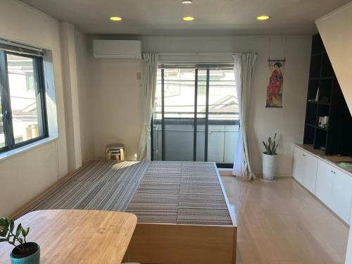 a room with a bed with a table and a window at Shine house warabi in Warabi