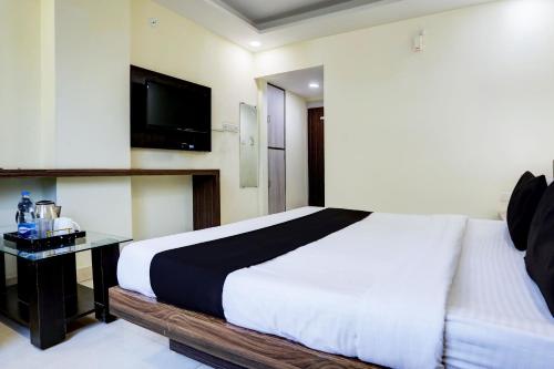 a bedroom with a bed and a tv on the wall at Super Townhouse Hoshangabad Road Near Aashima Mall in Bhopal