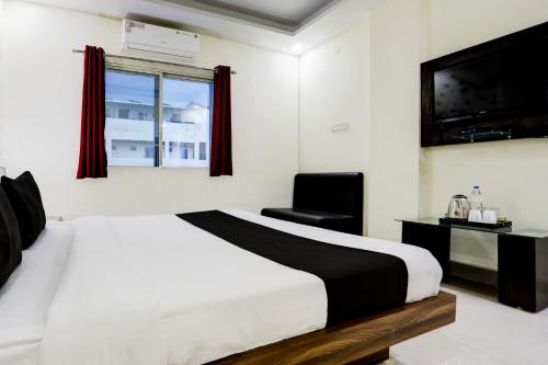 a bedroom with a bed and a chair and a television at Super Townhouse Hoshangabad Road Near Aashima Mall in Bhopal