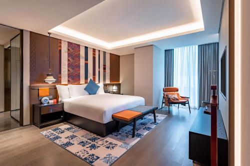 a hotel room with a bed and a chair at Hotel Indigo Jiuzhai by IHG in Jiuzhaigou