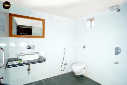 Un baño blanco con inodoro y espejo. en Golden Fort Resort, en Jaisalmer