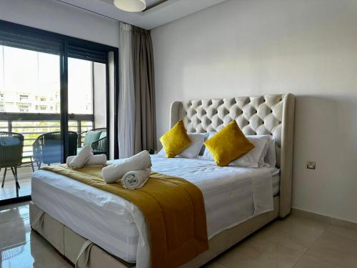 a bedroom with a large white bed with yellow pillows at APT Luxueux à 5 min de la Plage avec accès Piscine in Bouznika