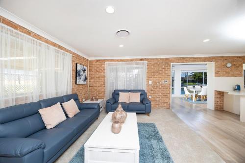 a living room with a blue couch and a brick wall at Castaway on King George in Forster