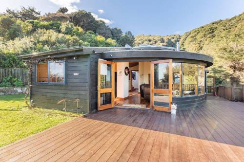 a small green house with a deck with a mountain at Sea views from holiday home in Lower Hutt