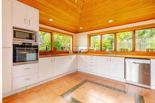 a kitchen with white cabinets and a wooden ceiling at Sea views from holiday home in Lower Hutt