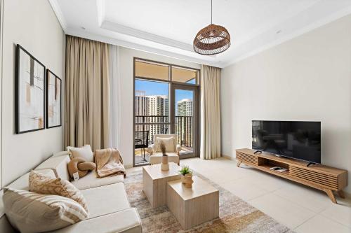 a living room with a couch and a television at Silkhaus Vacation Homes Chic and Cozy 1 BR Nearby Reem Park in Abu Dhabi