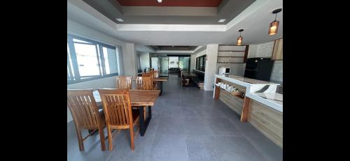 a dining room with a table and chairs and a kitchen at Na Care Hotel in Chaiyaphum