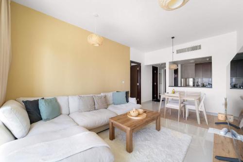 a living room with a white couch and a table at Silkhaus Vacation Homes Cozy 1BDR Near Reem Mall in Burooj Views in Abu Dhabi