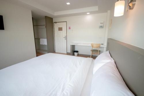 a bedroom with a white bed and a desk at Na Care Hotel in Chaiyaphum
