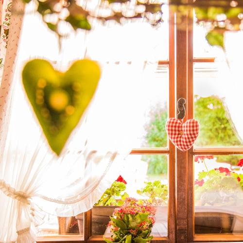a window with a green heart hanging from it at Kaisers Tanne - Premium Alles Inklusive Hotel in Breitnau